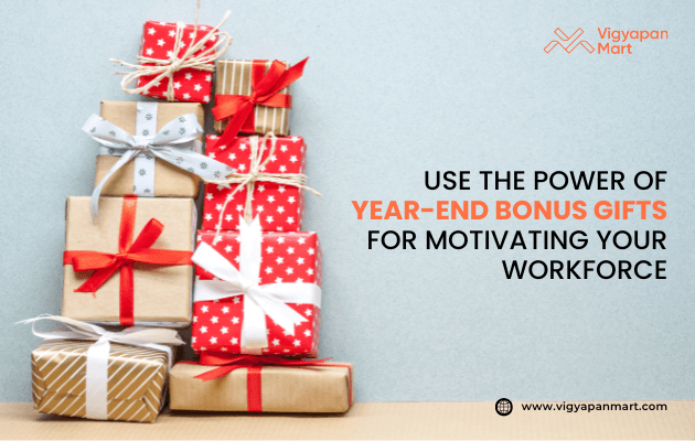 Stack of Christmas and year-end bonus gift boxes wrapped in red, gold, and patterned paper with festive ribbons. Promotional banner for Vigyapan Mart with text: "Use the power of year-end bonus gifts for motivating your workforce." Website: www.vigyapanmart.com
